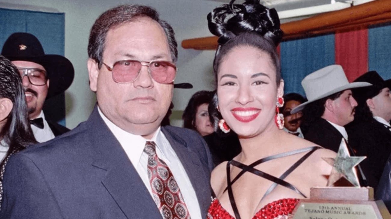 Abraham Quintanilla con lentes y mirada seria y su hija Selena de rojo con el cabello recogido sonriente en una entrega de premios