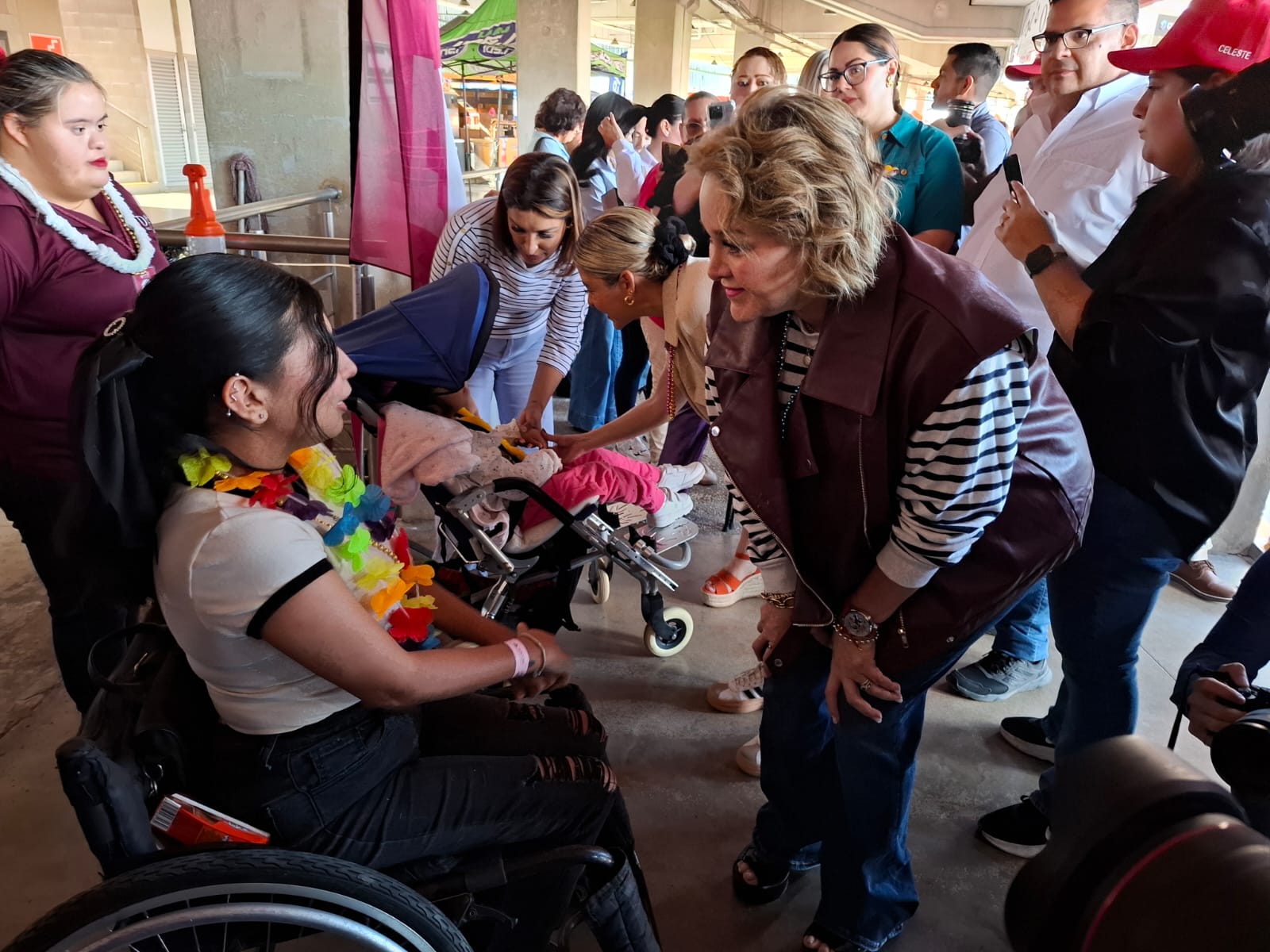 Eneyda Rocha Ruiz saludando a una muchacha en silla de ruedas mientras que detrás de ella hay mas personas en el festejo