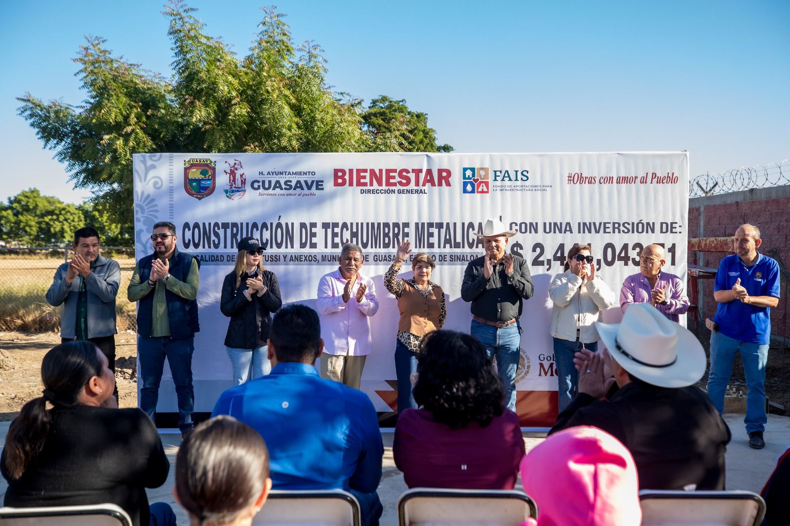 Personas levantando la mano en una tarima con personas observando