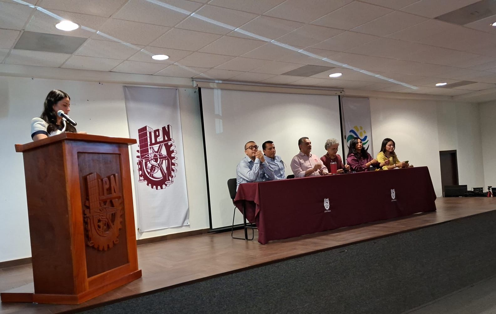 Personas sentadas y una persona dirigiendo un evento
