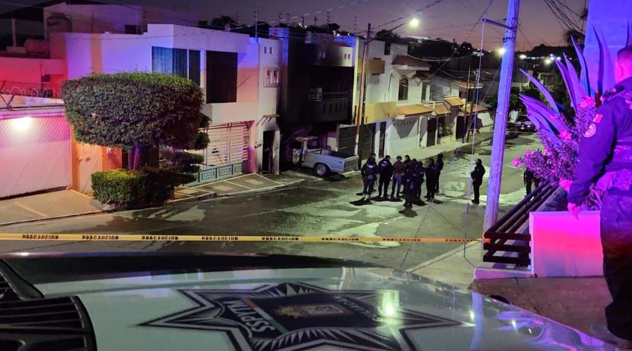 Agentes policiacos así como unidades de seguridad en una calle de un vecindario frente a una casa incendiada