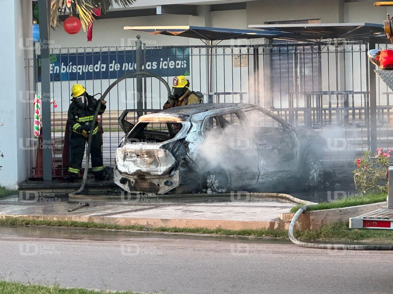 Carro incendiado junto a dos elementos de bomberos