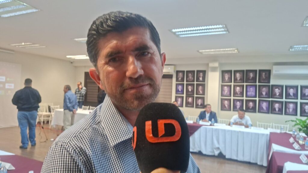 Hombre viendo hacia el frente con un micrófono negro con las letras LD en color naranja