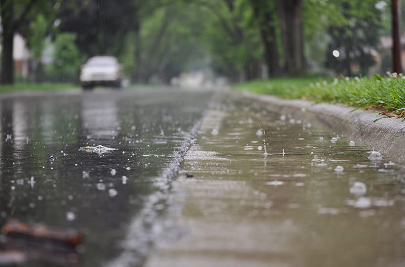 Gotas de lluvia formando un charco en la calle.