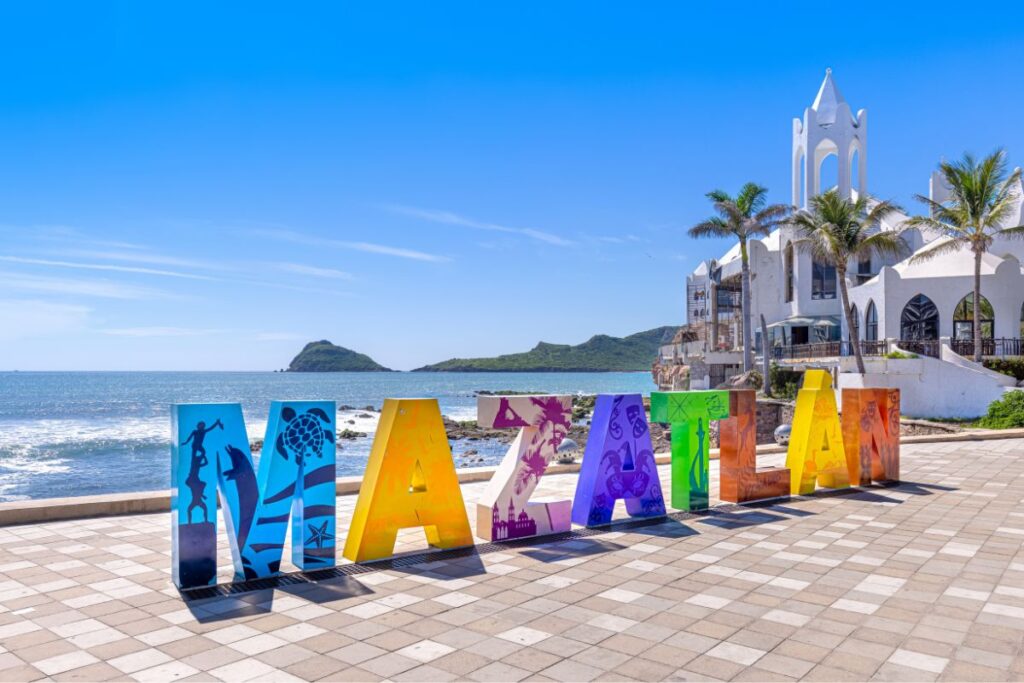 Letras en diferentes colores de la palabra MAZATLÁN en la zona costera, al fondo se ve el mar
