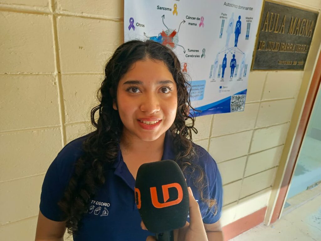 Mujer hablando al frente con un micróffono negro con las letras LD en color naranja