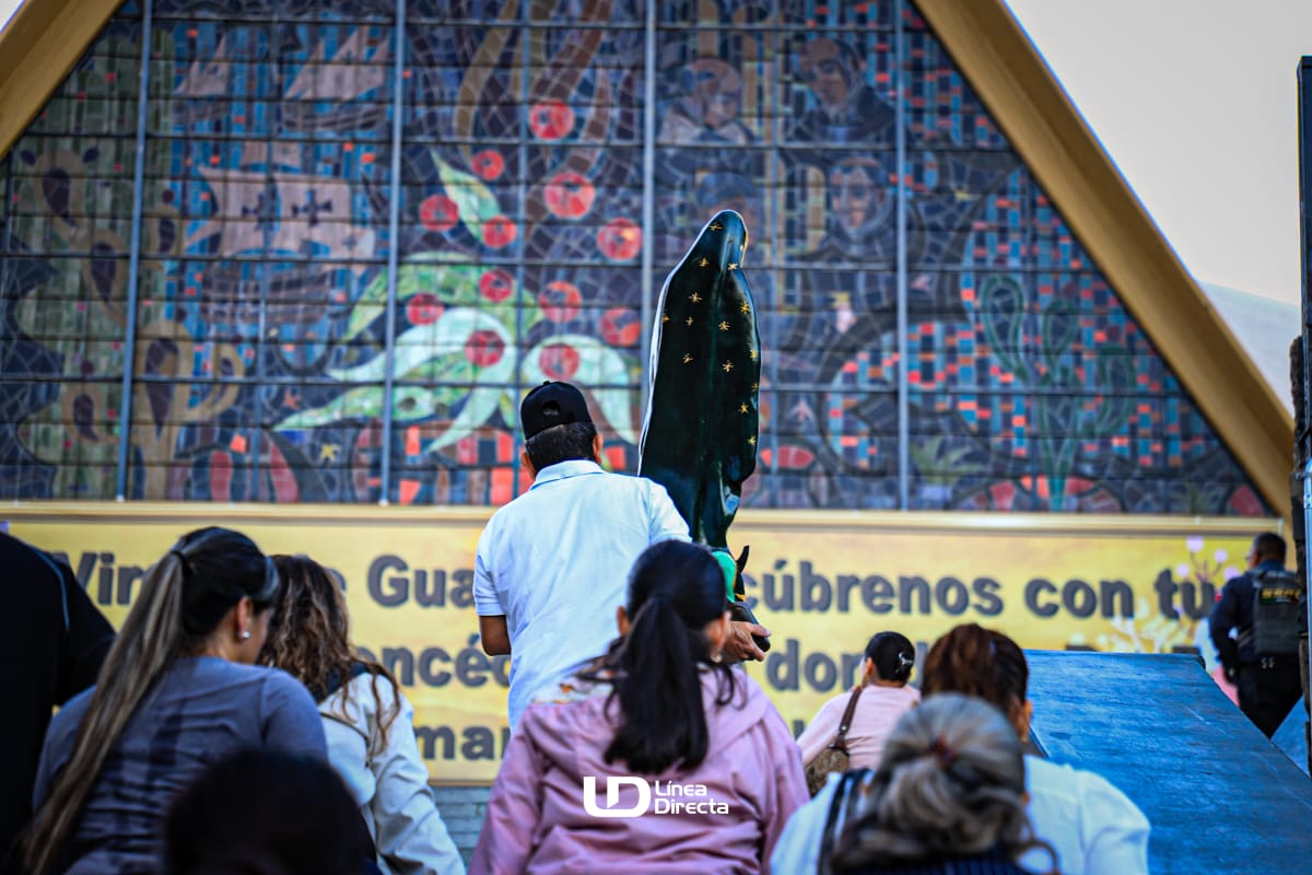 Personas subiendo escleras, una de ellas lleva una estatua de la virgen en sus brazos