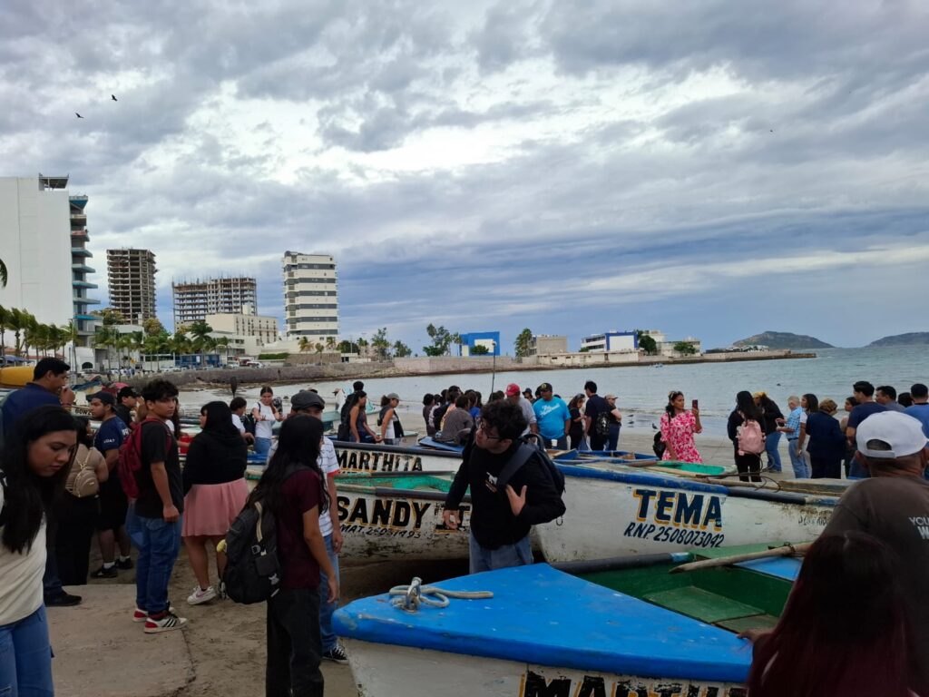 Personas junto a lanchas de pescadores en Mazatlán