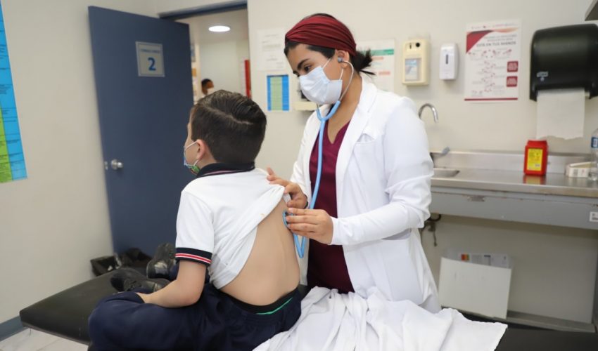 Médica atendiendo a un niño sentado en una camilla