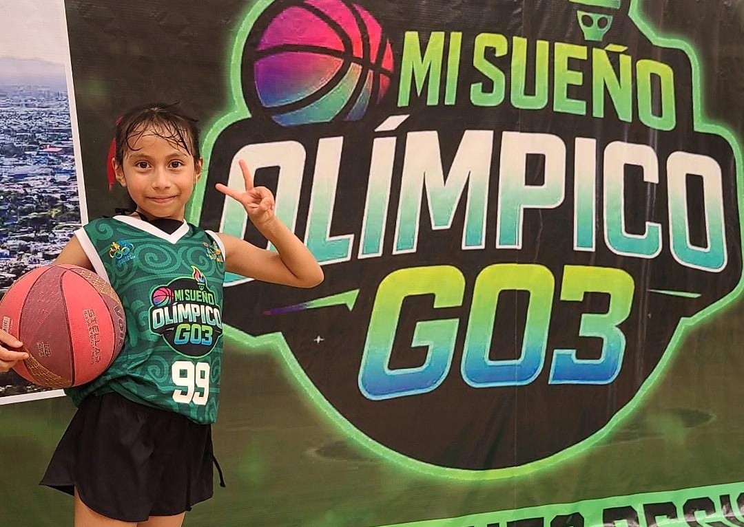 Niña basquetbolista Mía Luciana López Jackson saluda soteniendo un balón de basquetbol