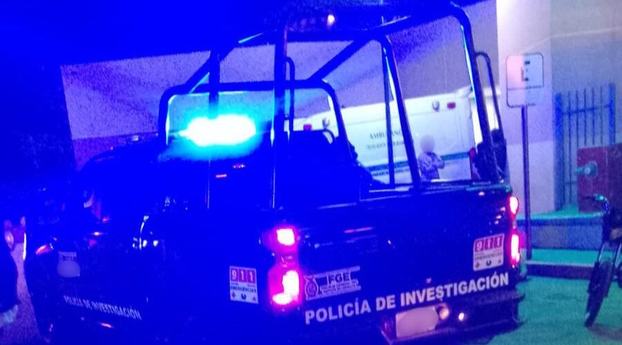 Patrulla con las luces encendidas afuera de un hospital, al fondo se observa una unidad de emergencia