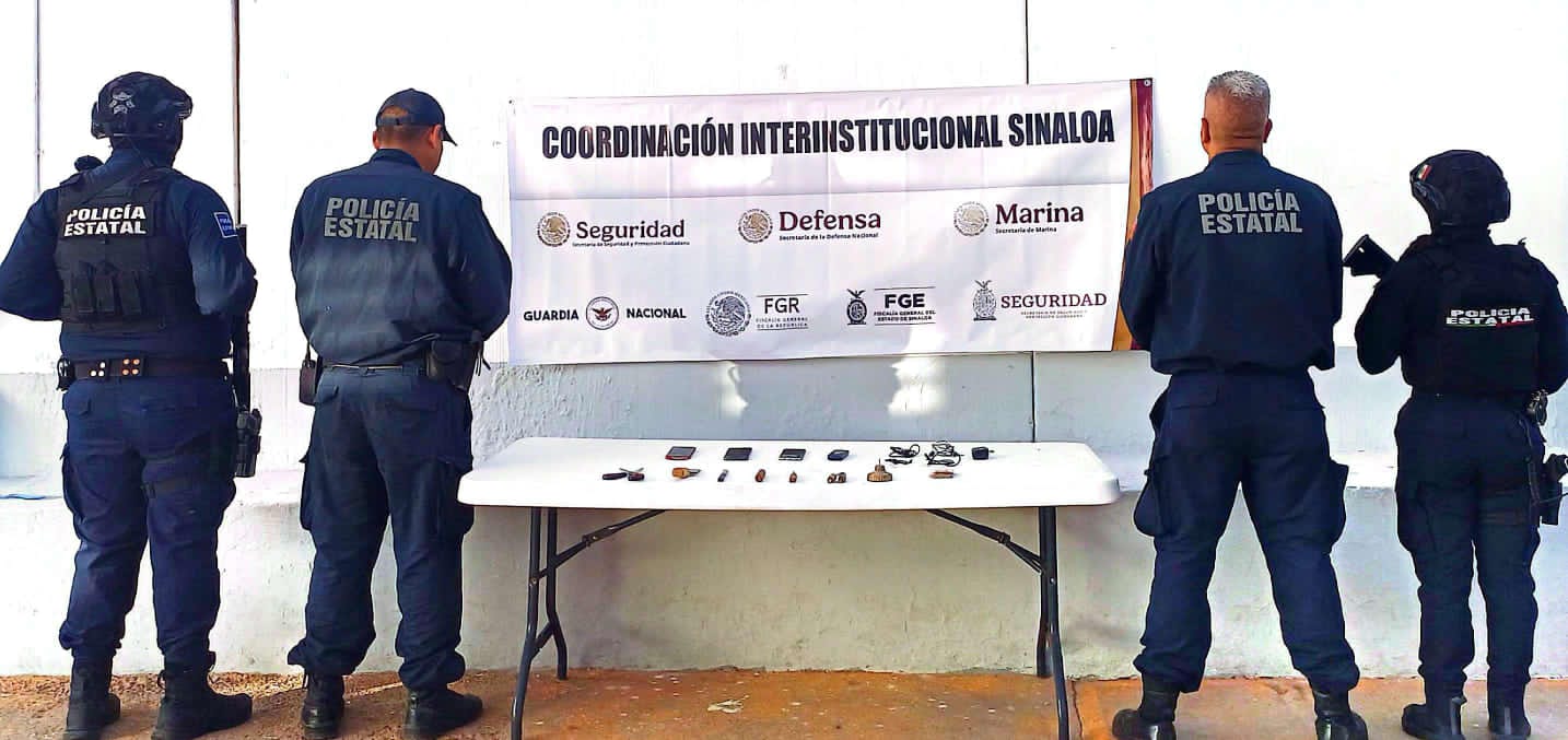 Elementos de seguridad de espaldas junto a una mesa con las cosas que aseguraron dentro del penal de goros II