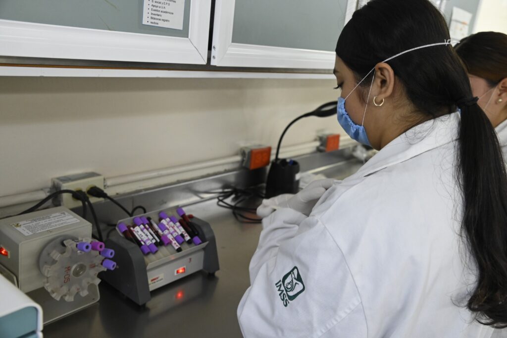 Persona con bata blanca y tubos de ensayo en laboratorio