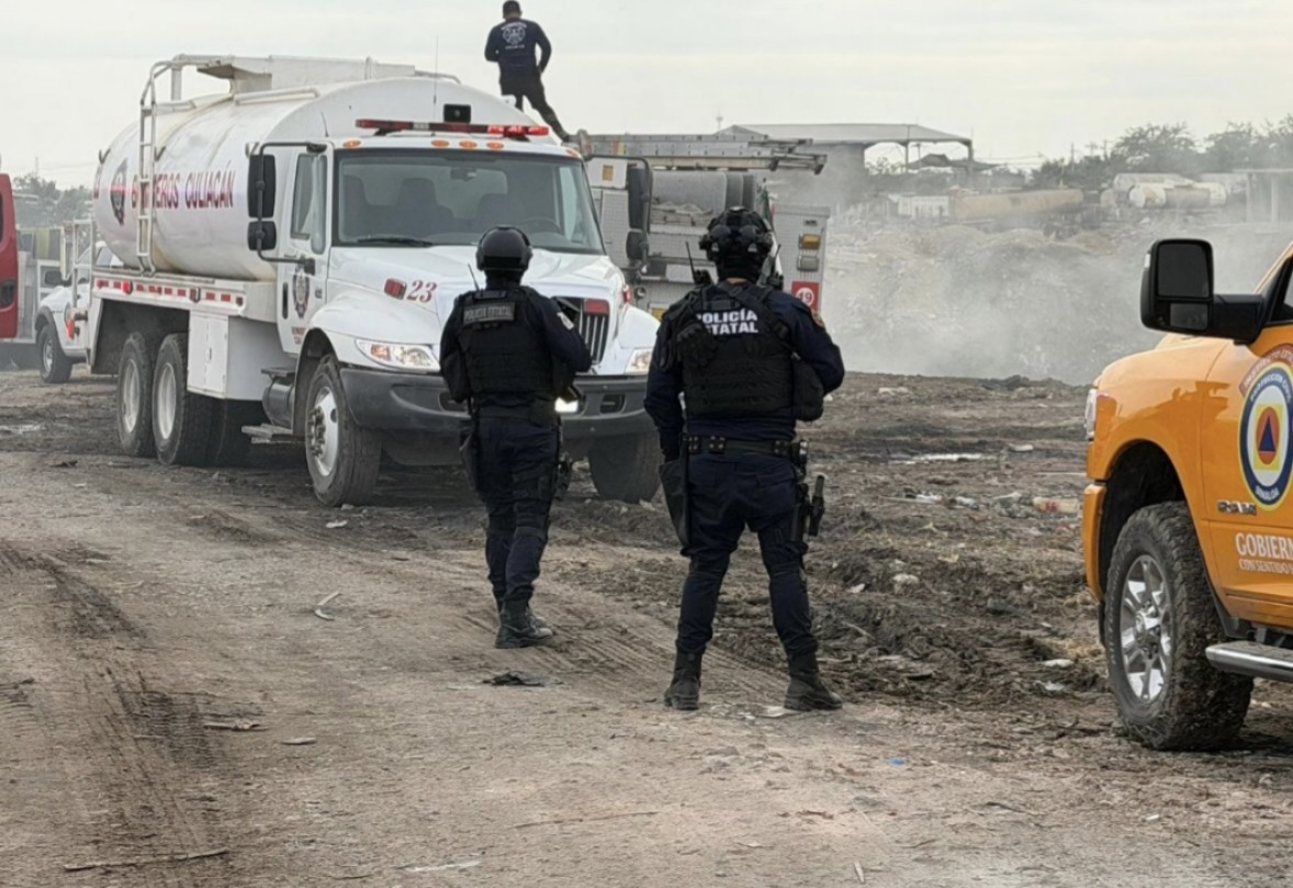 Elementos de seguridad y de bomberos sofocando un incendio en un basurón