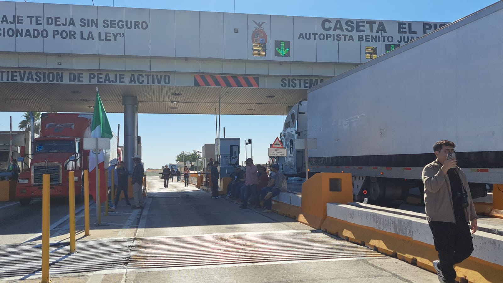 PErsonas sentadas y caminando en una caseta de peaje