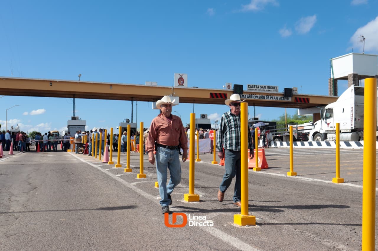 Dos personas caminando y al fondo una caseta de peaje