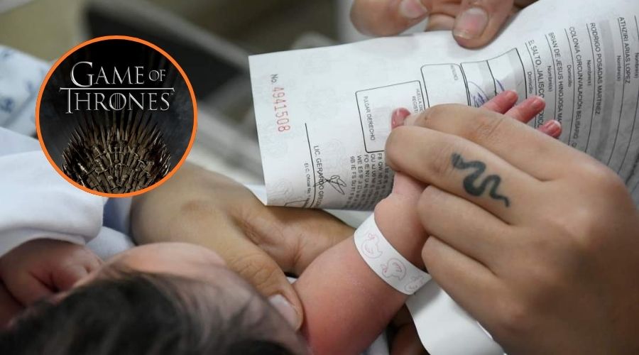 Bebé con la mano en un papel colocando la huella siento agarrado con las manos de otras personas y en un círculo una imagen de un banner de Game Of Thrones