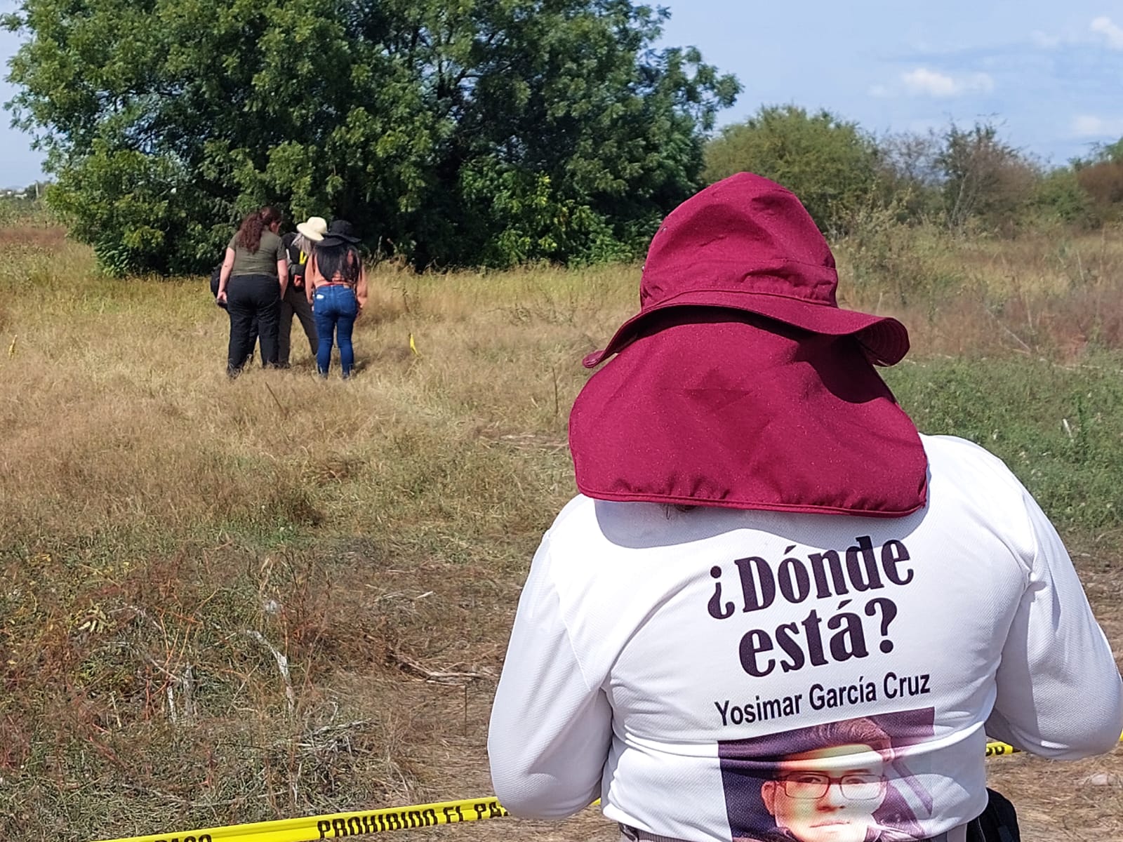 Un campo abierto asegurado donde se ve a personas realizando una búsqueda