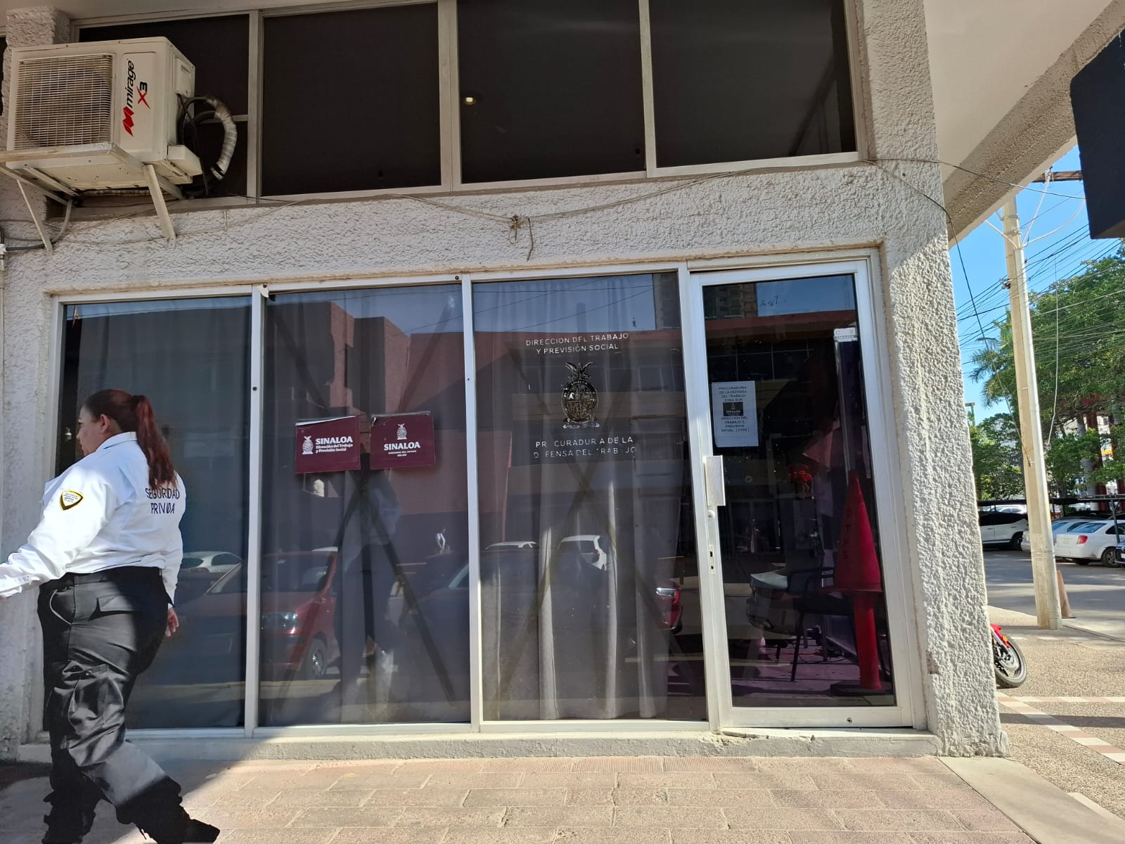 Puertas de vidrio de un edificio y un elemento de vigilancia femenino caminando