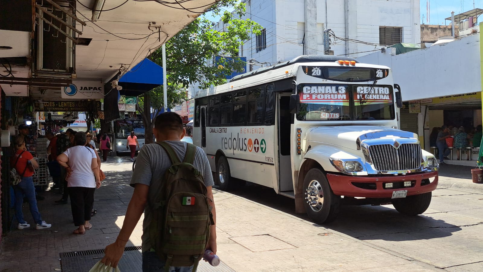 Transporte publico estacionado en vialidad y personas transitando