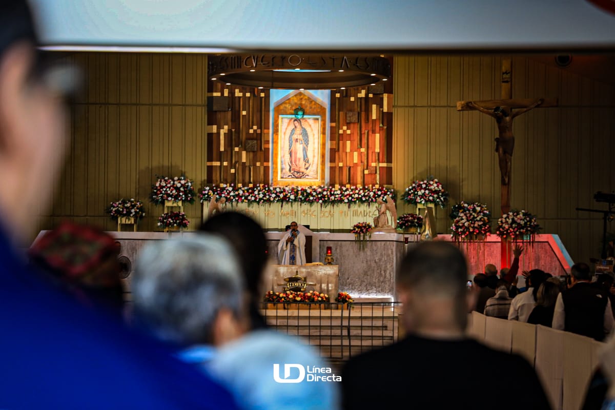 Personas en misa y al fondo una imagen de la Virgen de Guadalupe