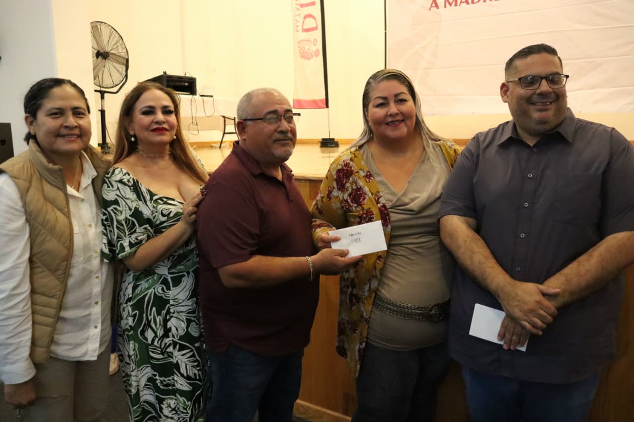 PErsonas de pie en un foro y dos personas sosteniendo una hoja