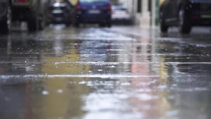 Lluvia en la calle creando charcos ligeros