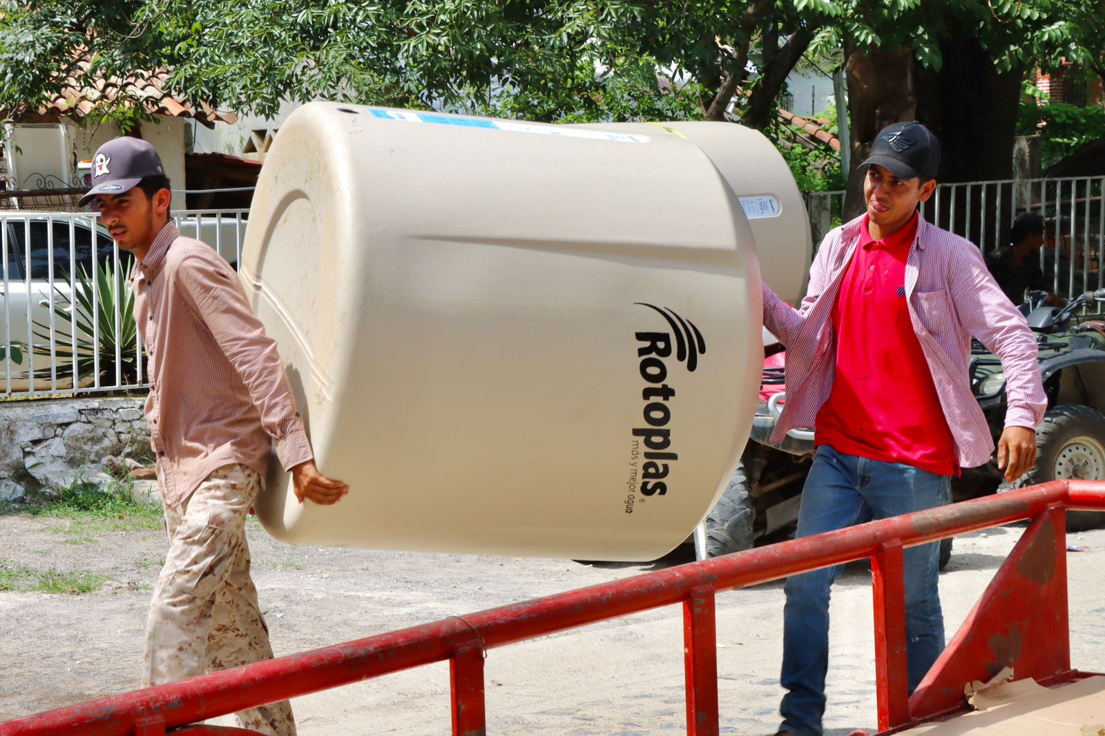 Entrega de tinacos: dos hombres cargando tinacos