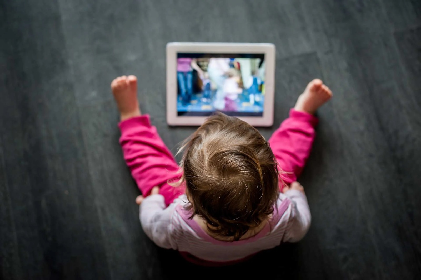 Niña con pantalla en el suelo
