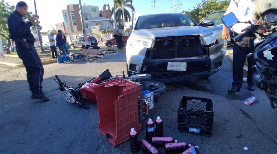 Camioneta gris y al frente una motocicleta tirada en una calle junto a botellas de jamaica