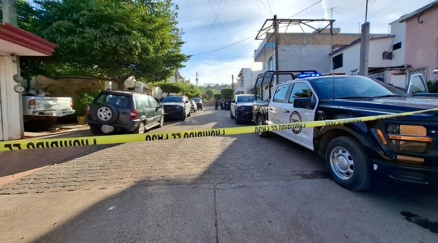 Unidades policiacas en un vecindario y una cinta amarilla de precaución