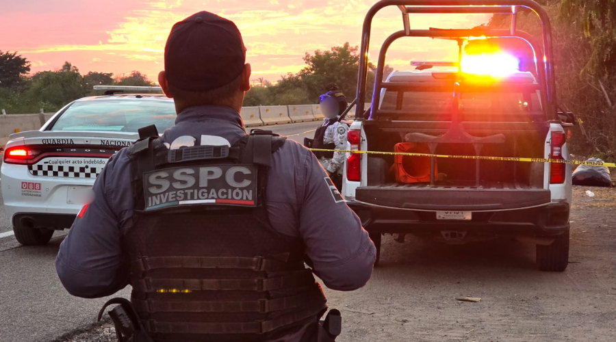 Elementos de seguridad de espaldas y encapuchados junto a sus unidades