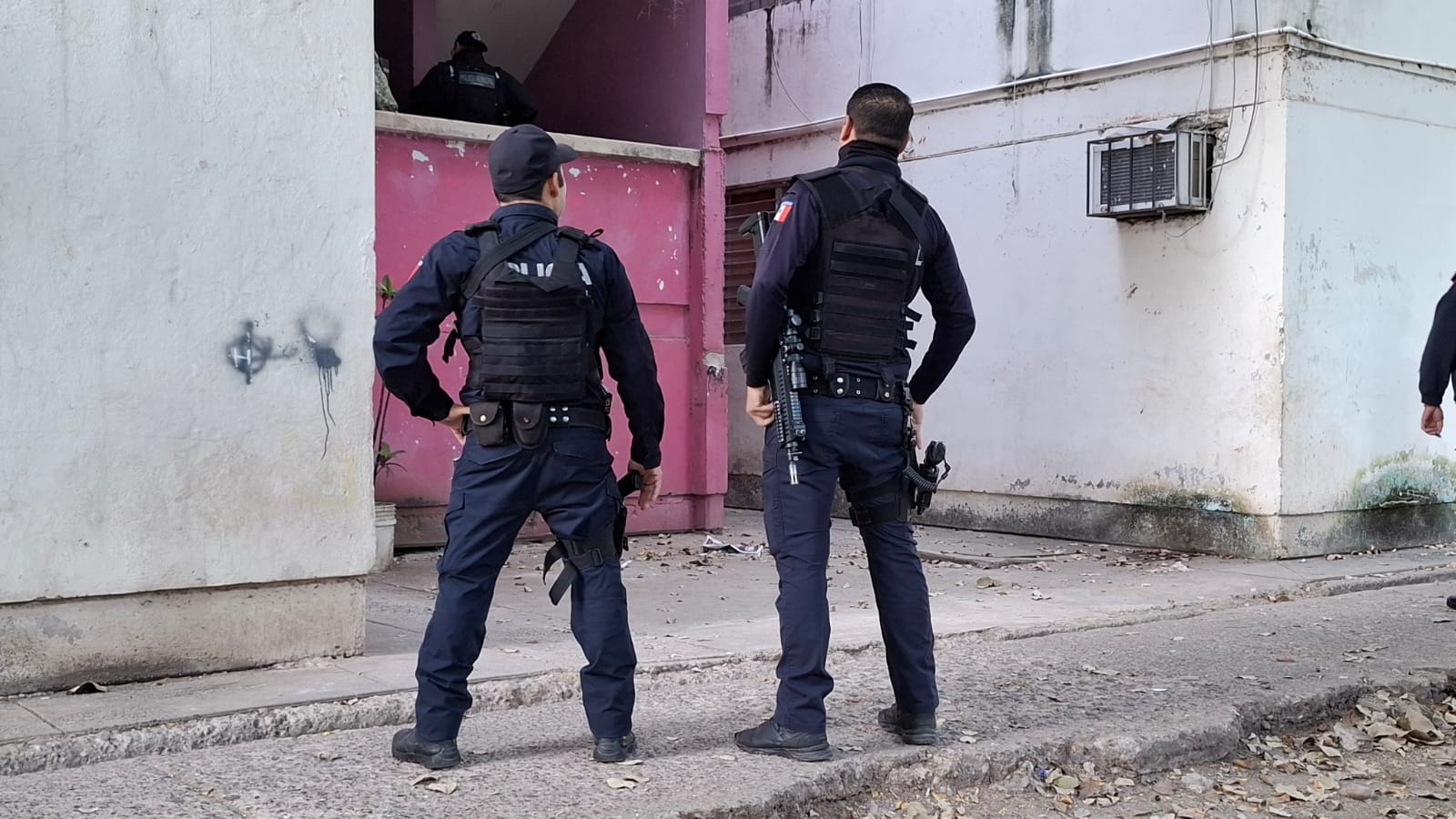 Elementos policiacos de espalda afuera de unos departamentos