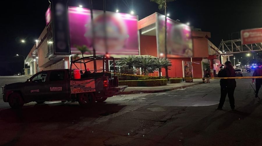 Fachada de un casino en colores rosa, se observa una unidad policiaca así como elementos desplegados y una cinta amarilla resguardando la zona en una calle