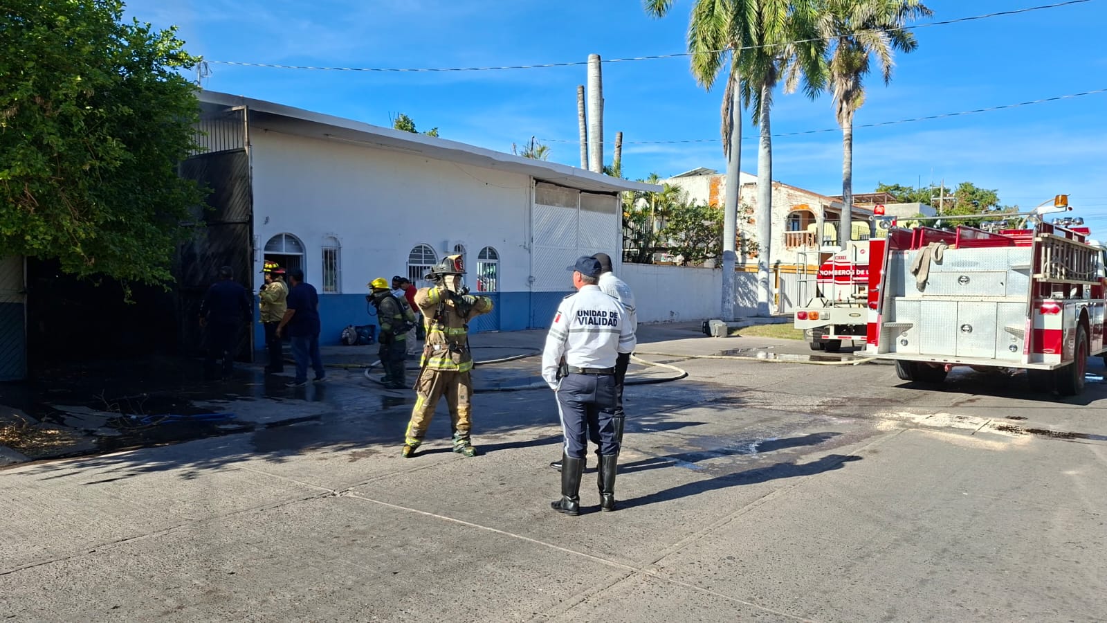 Elementos del cuerpo de bomberos y policiacos desplegados en una calle junto a unidades de emergencia