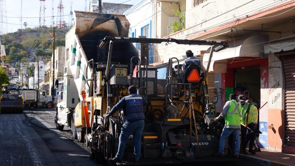 Trabajadores junto a maquinaría en trabajos de pavimentación
