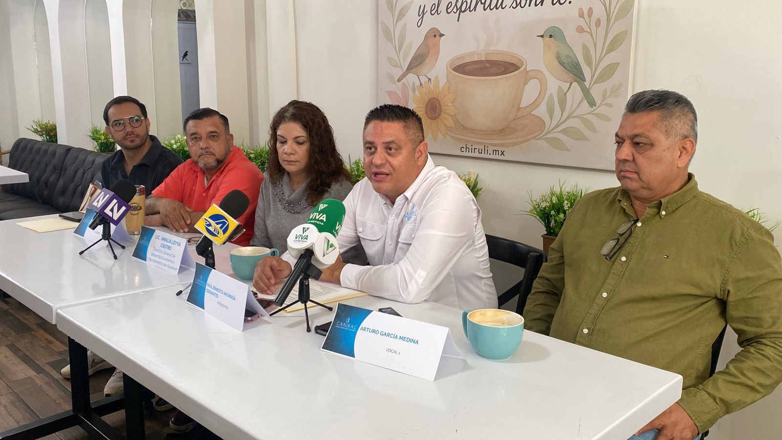 PErsonas sentadas en una mesa durante una rueda de prensa