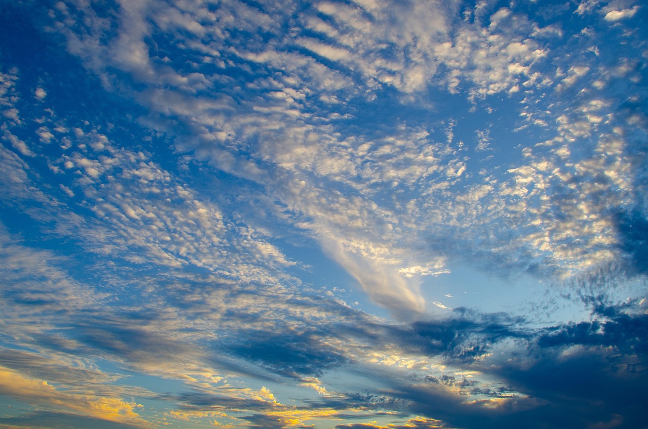 Cielo azul con nubes con tonos naranjas y amarillos por el sol