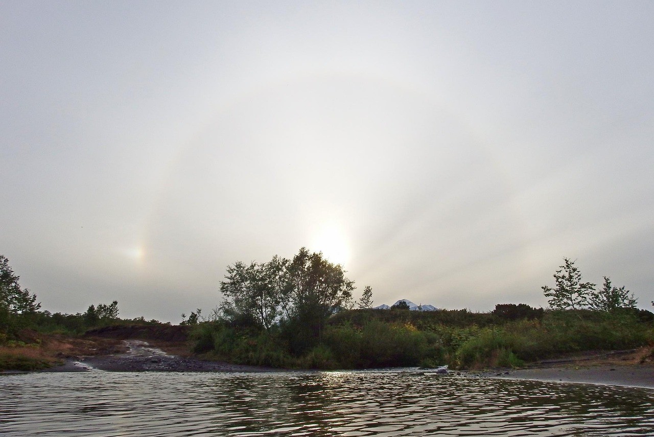 Cielo nublado en un lago con rayos de sol saliendo entre las nubes