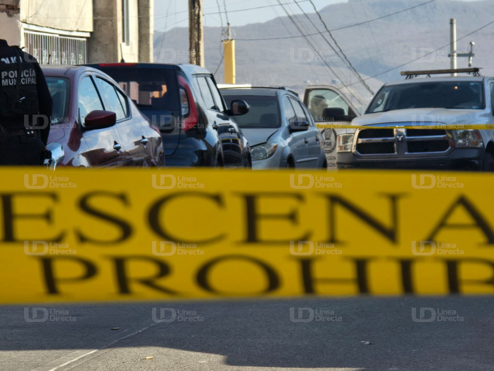 Cinta amarilla de precaución y al fondo se observan carros y una unidad policiaca