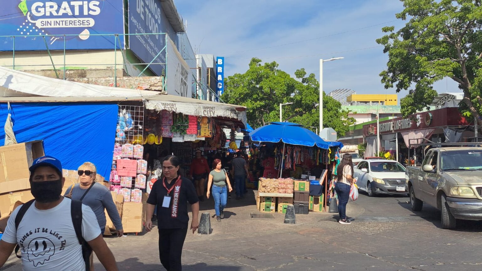 Personas caminando en una calle junto a negocios en la banqueta
