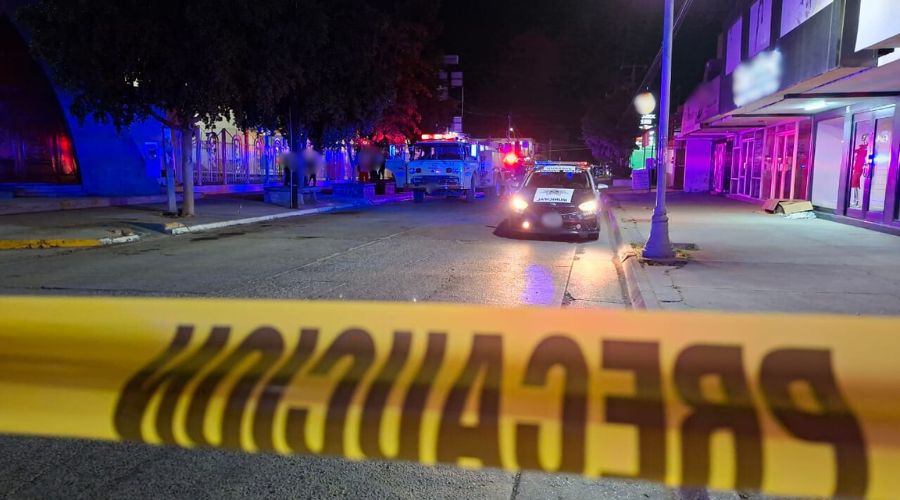 Cinta amarilla y al fondo unidades de emergencia con las luces encendidas en una calle