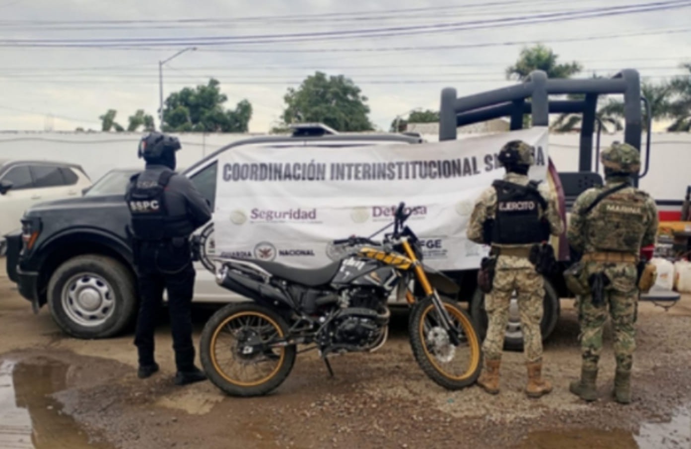 Autoridades del Grupo Interinstitucional junto a la motocicleta asegurada.