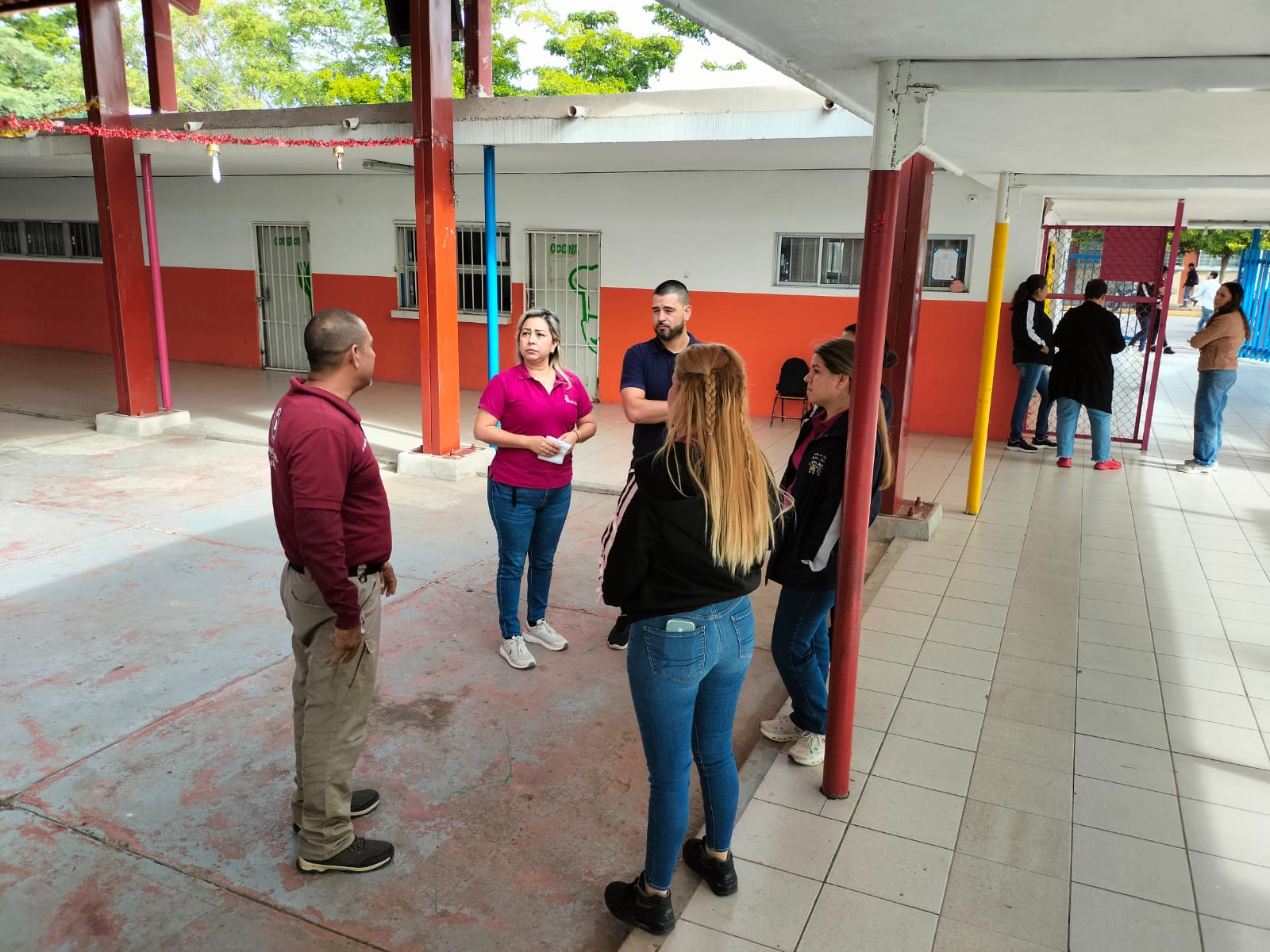 Autoridades escolares y de protección civil hablando al interior de una escuela