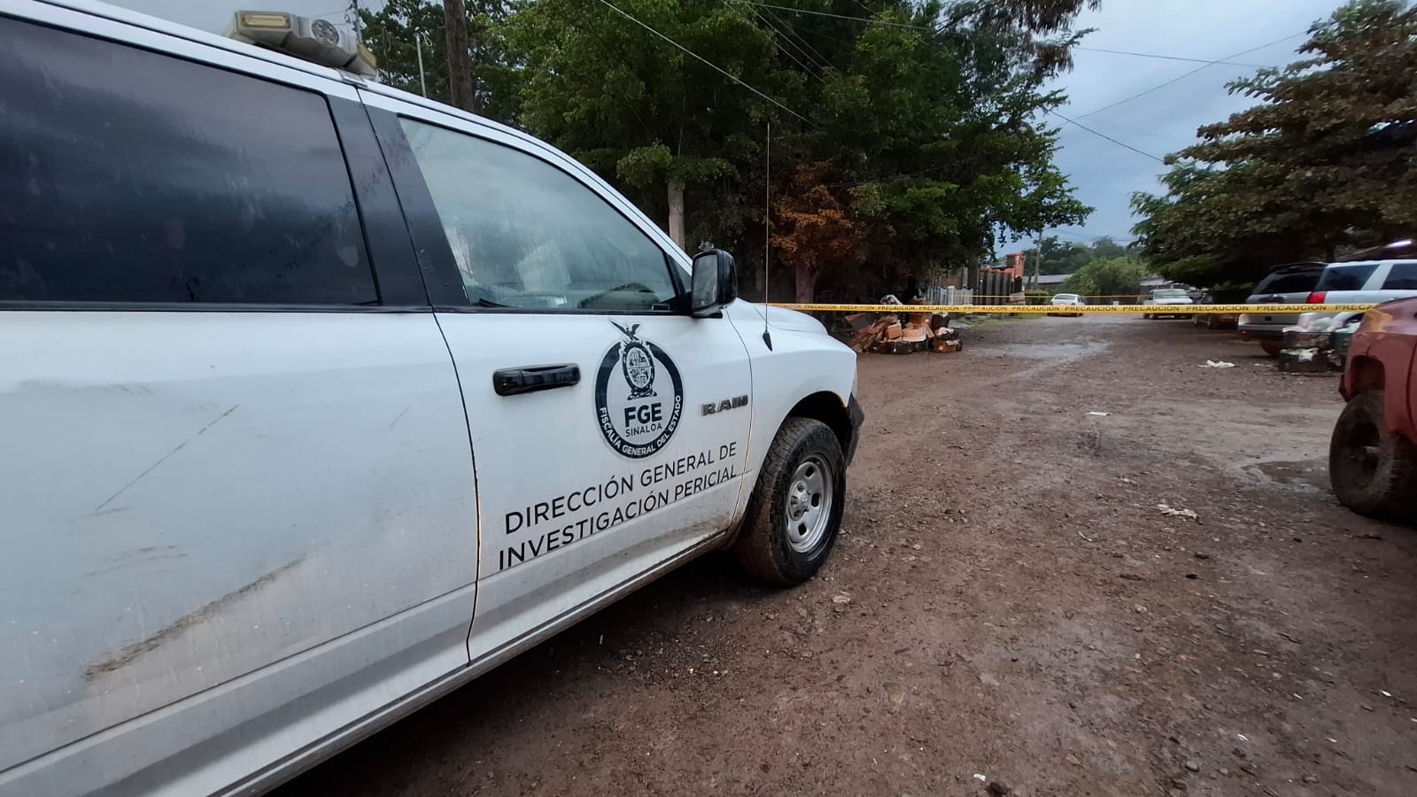 Unidad de la FGE en una calle de terracería y al fondo se observa una cinta amarilla de precaución