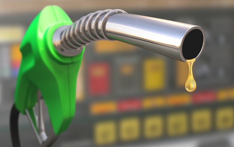 Imagen ilustrativa de una manguera dispensadora de gasolina color verde con liquido amarillo derramandose