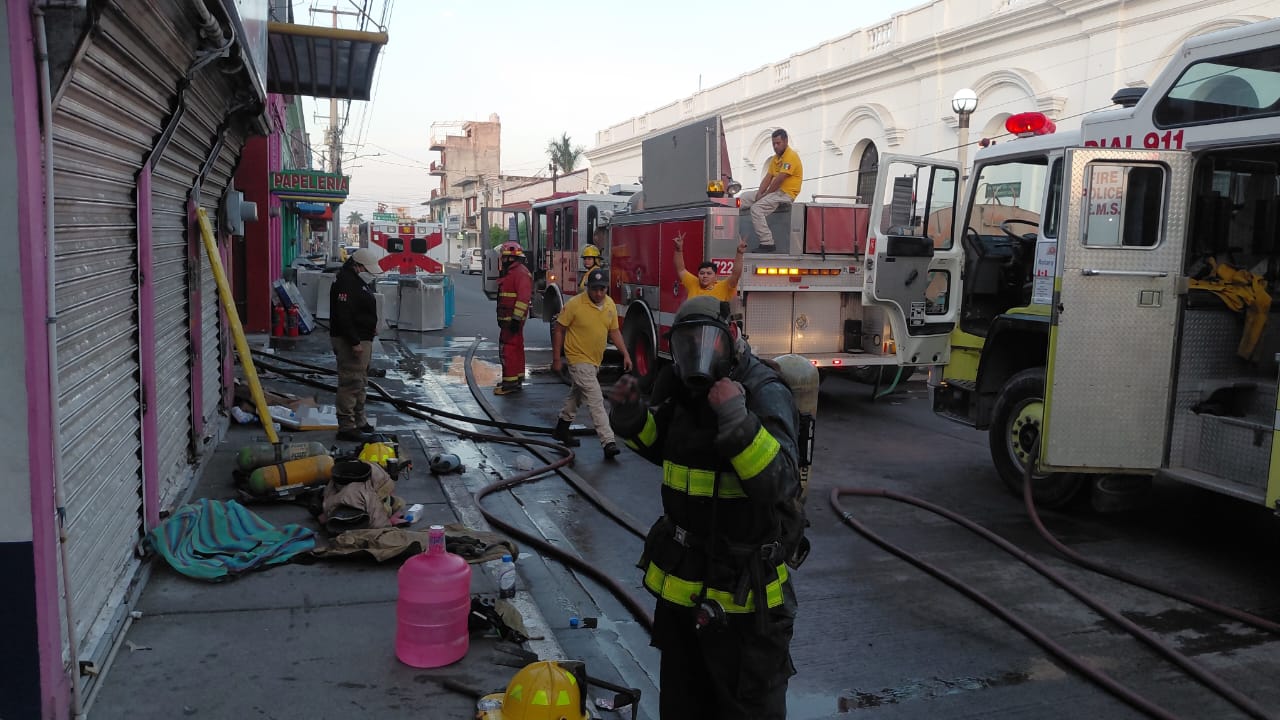 Personal de bomberos en una calle junto a una unidad de bomberos
