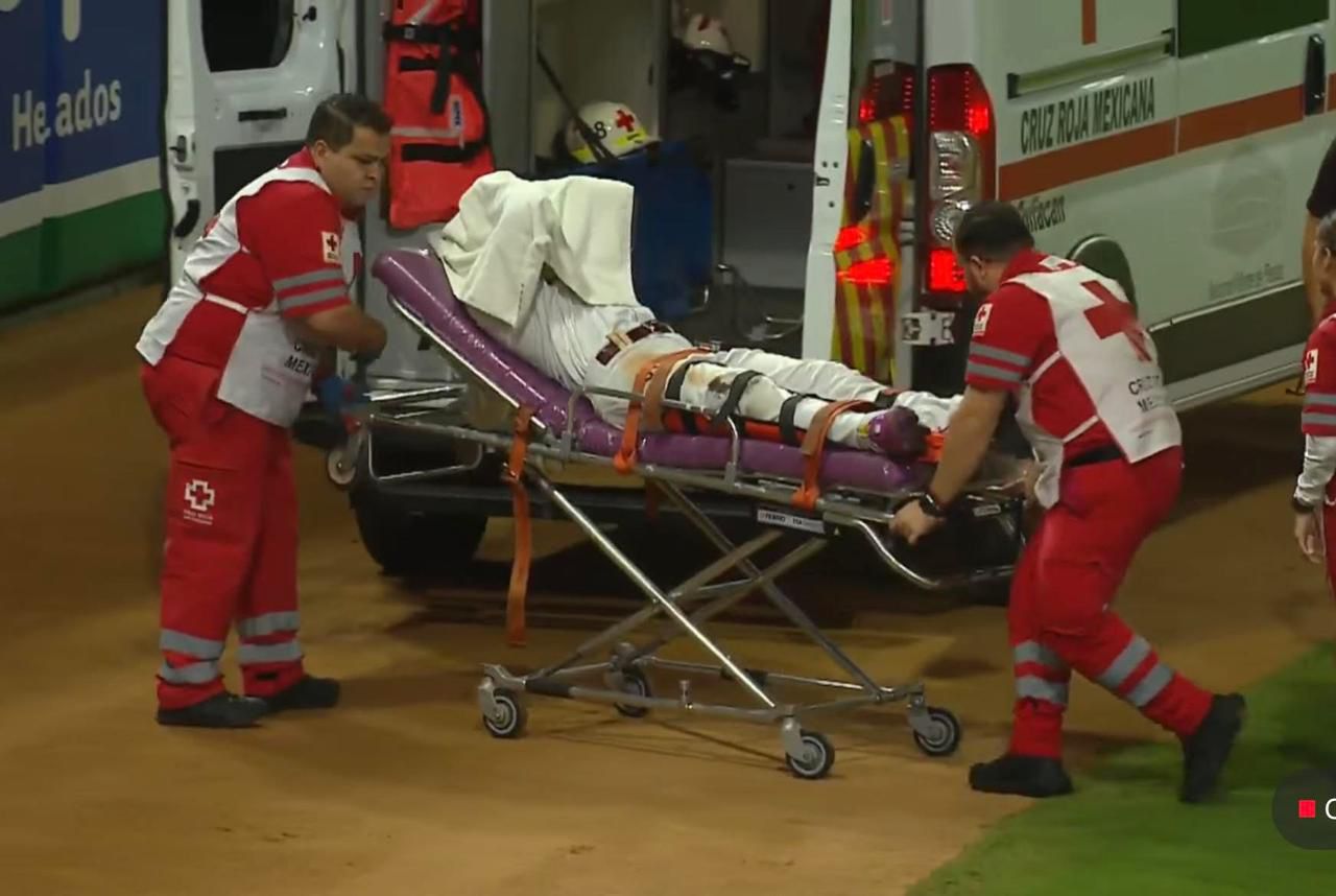 Jugador de Tomateros en un camilla y ambulancia de Cruz Roja