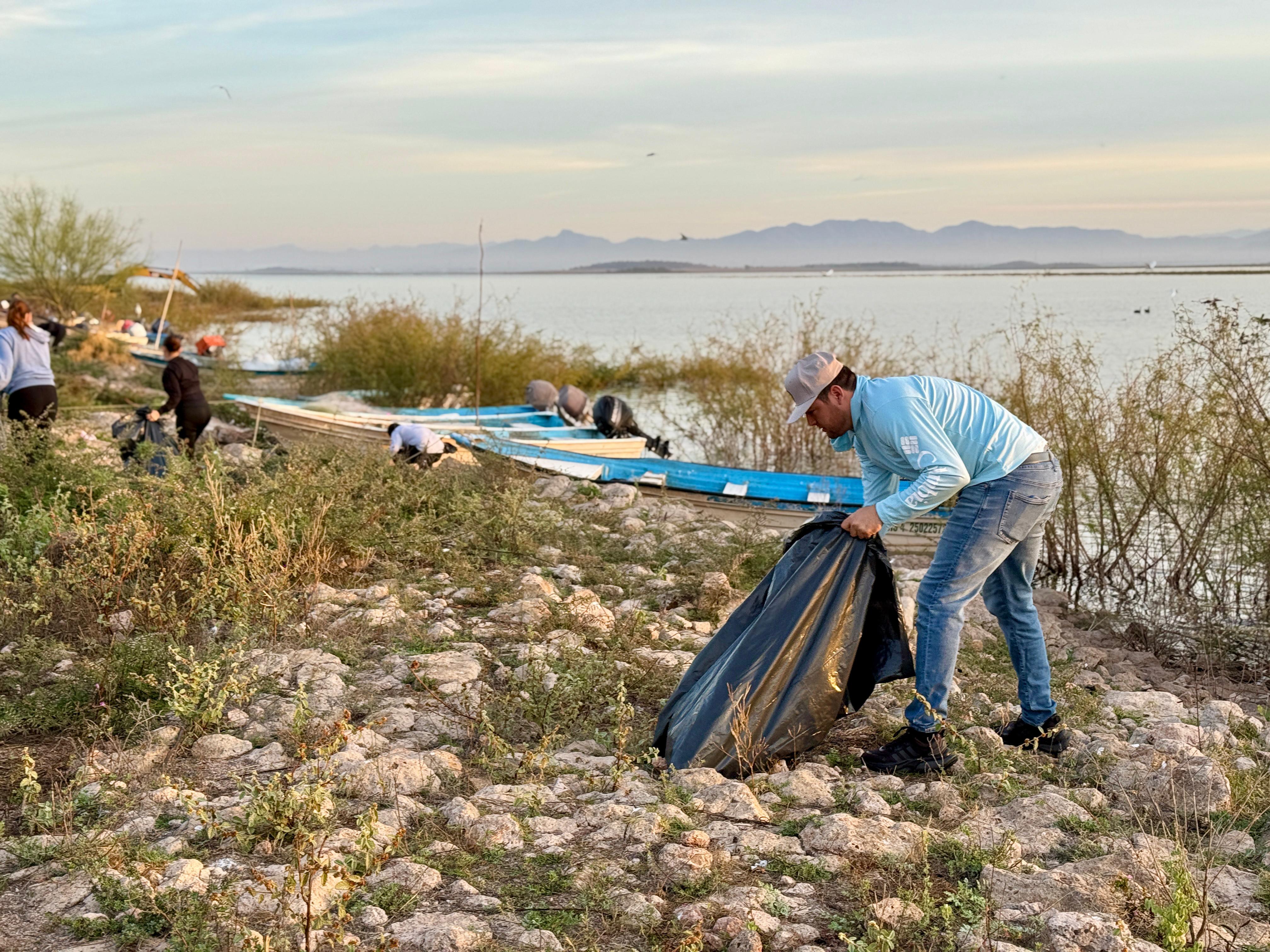 Personas limpiando y recogiendo basura cerca de una presa