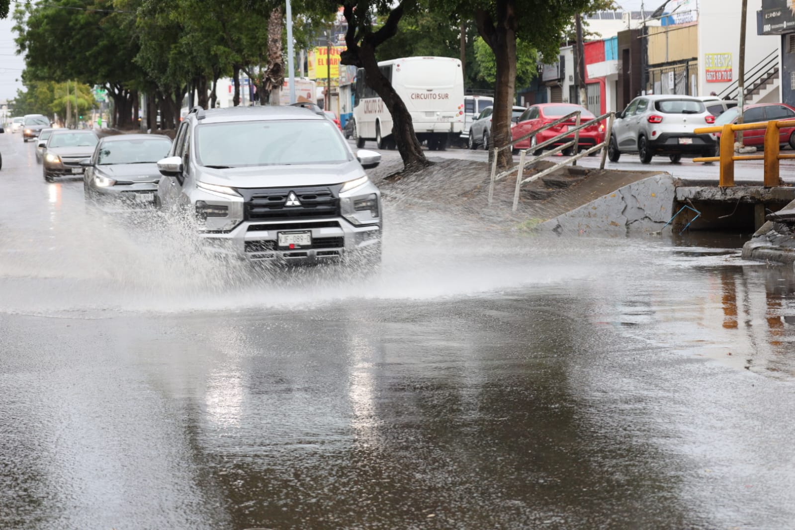 Carros en una calle con charcos de agua por las lluvias